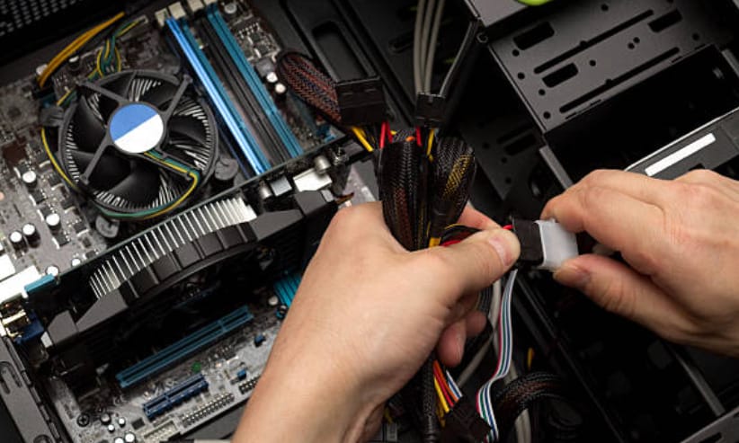 A person is checking for connectivity with wires of a computer's power supply