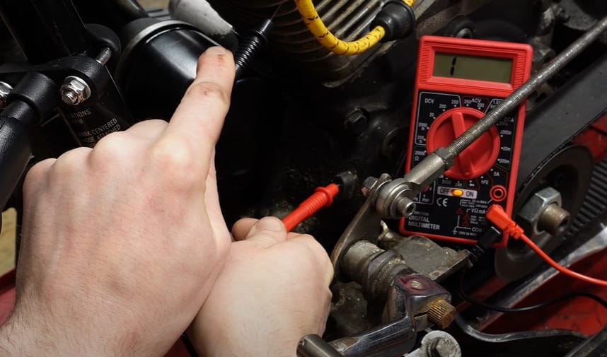 A person using a multimeter to test the stator on a motorcycle