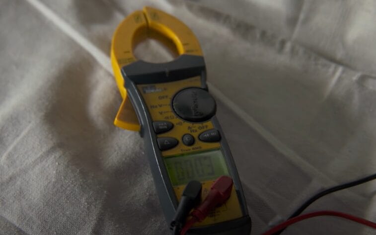 A digital clamp meter with no ground wire, placed on a white sheet