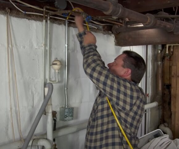 A man is working on wiring on the pipe