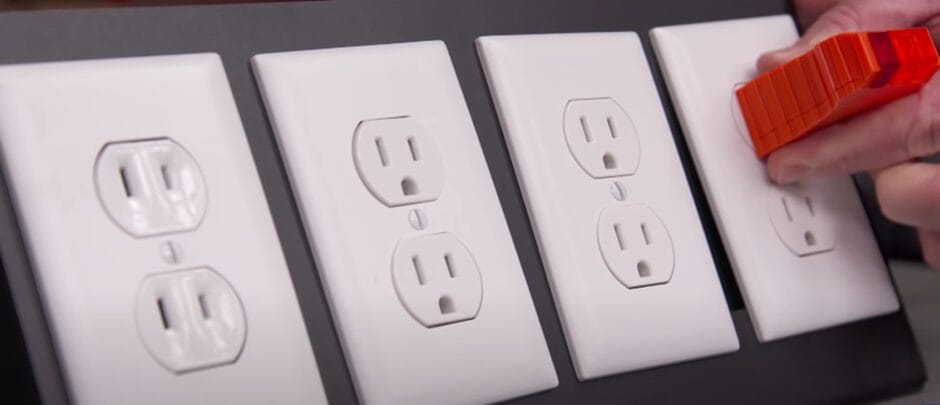 A person is testing the four outlets on the wall with a voltage tester tool