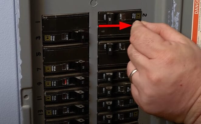 A person is pointing at a circuit breaker in a panel