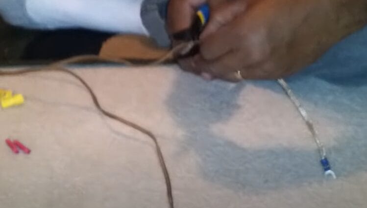 A man is diligently splicing speaker wire on the floor