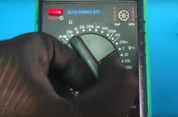 A person using a multimeter to test a 5 pin relay on a blue background.