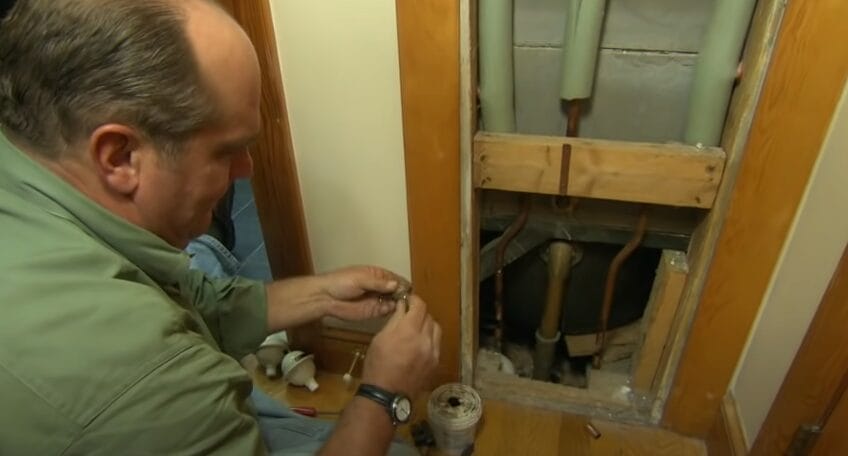A man installing a water hammer arrestor on a pipe