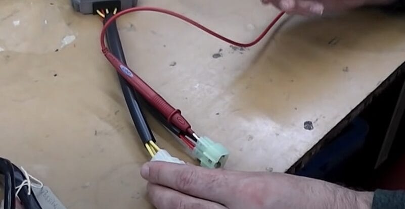 A person is testing the rectifier diode with a multimeter