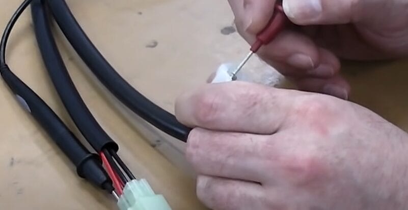 A person is testing a rectifier with a multimeter
