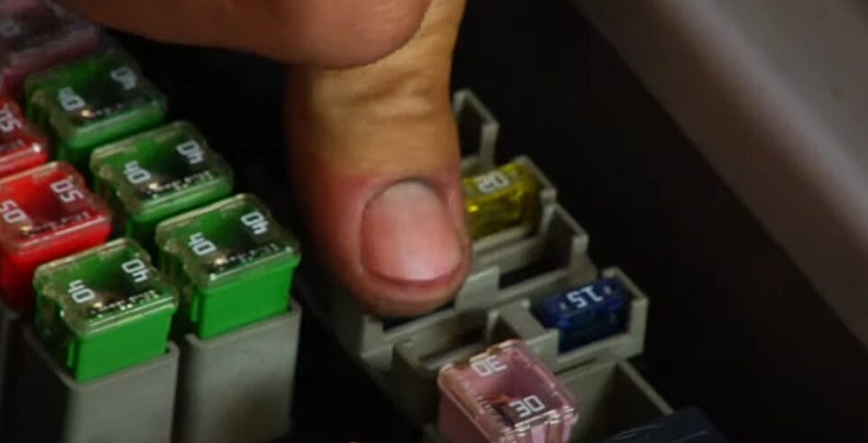 A mechanic pointing at a fuse of a car