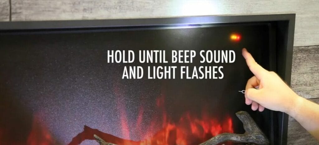 Looking to reset your electric fireplace? This man is pointing to a fireplace that says "hold" with beef sound and light flashes.