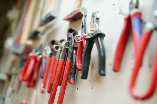 dIfferent pliers and hammers hang on wall