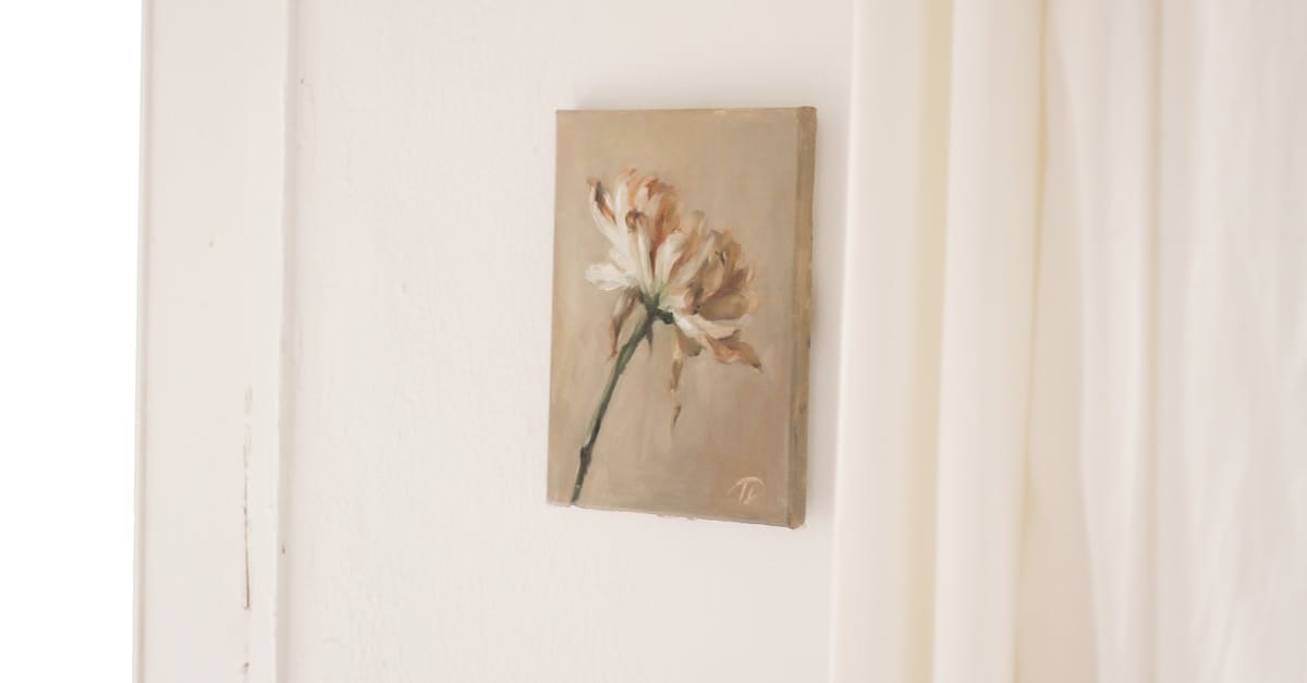 A small, beige-toned painting of a single white flower with a green stem hangs on a white wall near light-colored curtains.