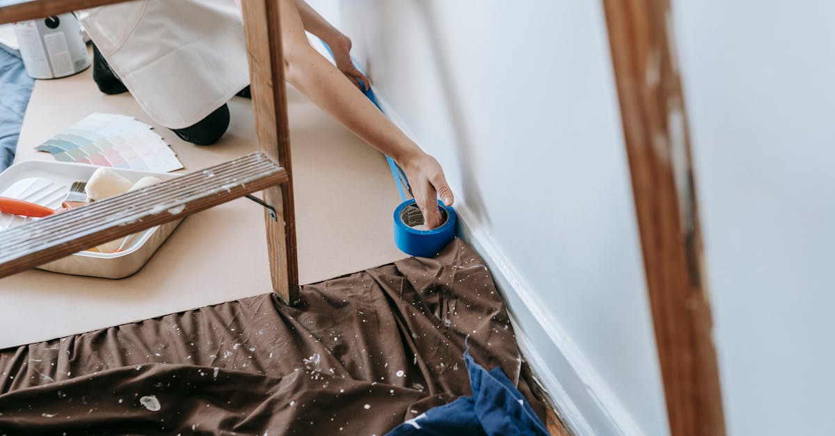 woman preparing room for painting with adhesive tape and tools home renovation project