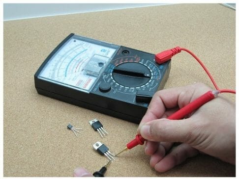 hands holding the multimeter tips and testing