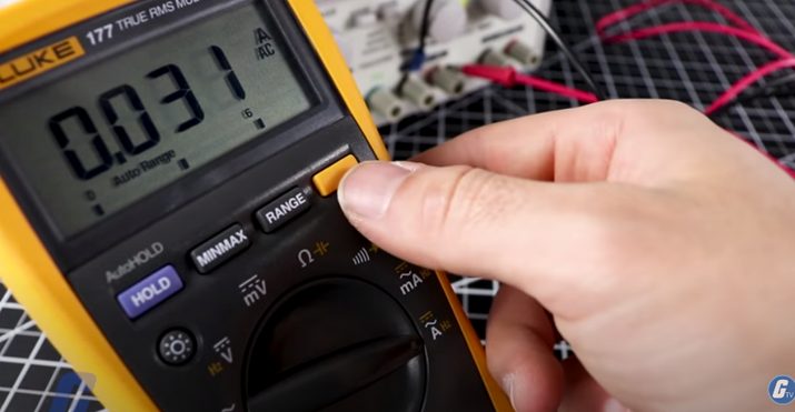 a man's hand holding a multimeter