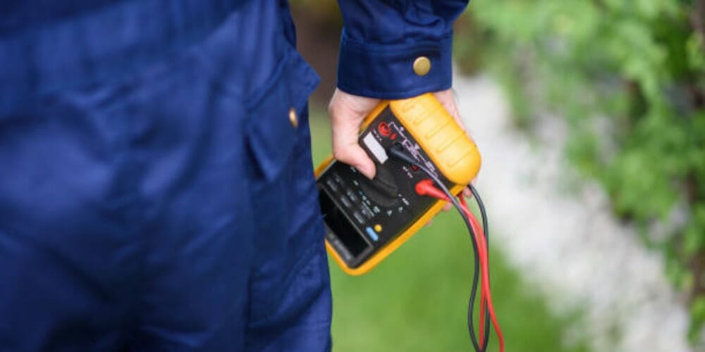 man in blue safety suit holding a yellow multimeter