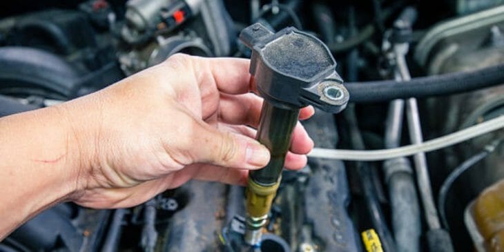 mechanic's hand holding an ignition coil