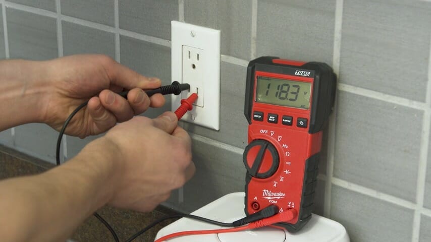 technician testing outlet's voltage using multimeter