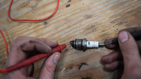 technician testing spark plug with multimeter
