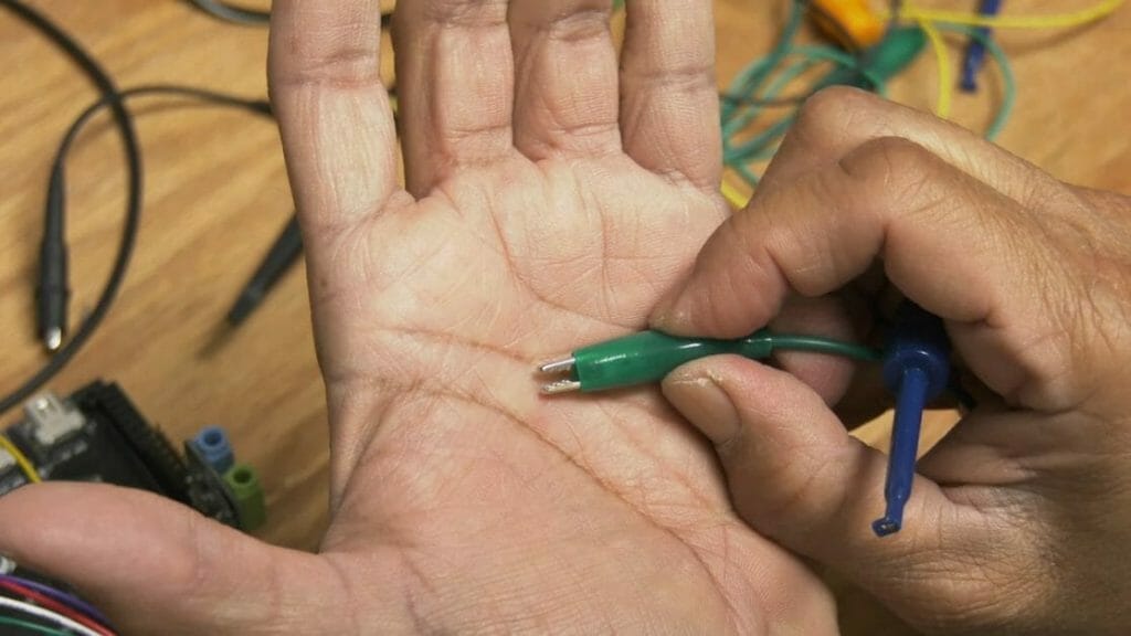 alligator clip probes in a man's palm