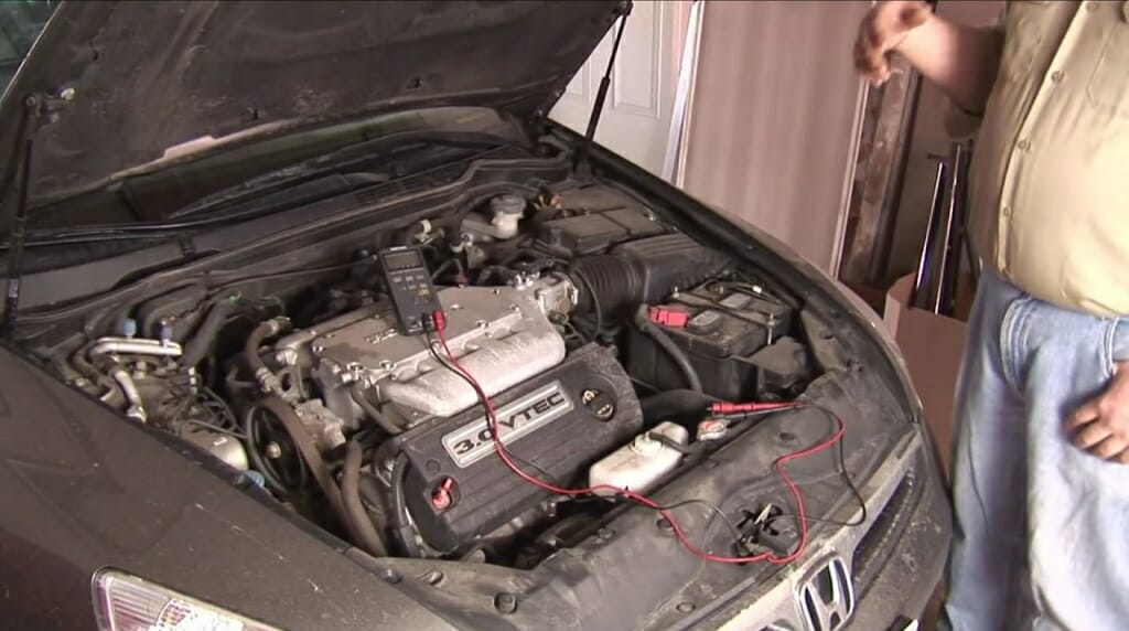 a man setting up the multimeter at the car hood