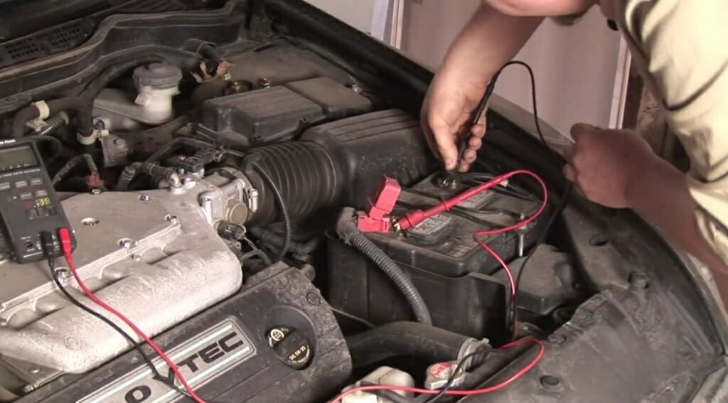 a man connecting the multimeter leads to the battery
