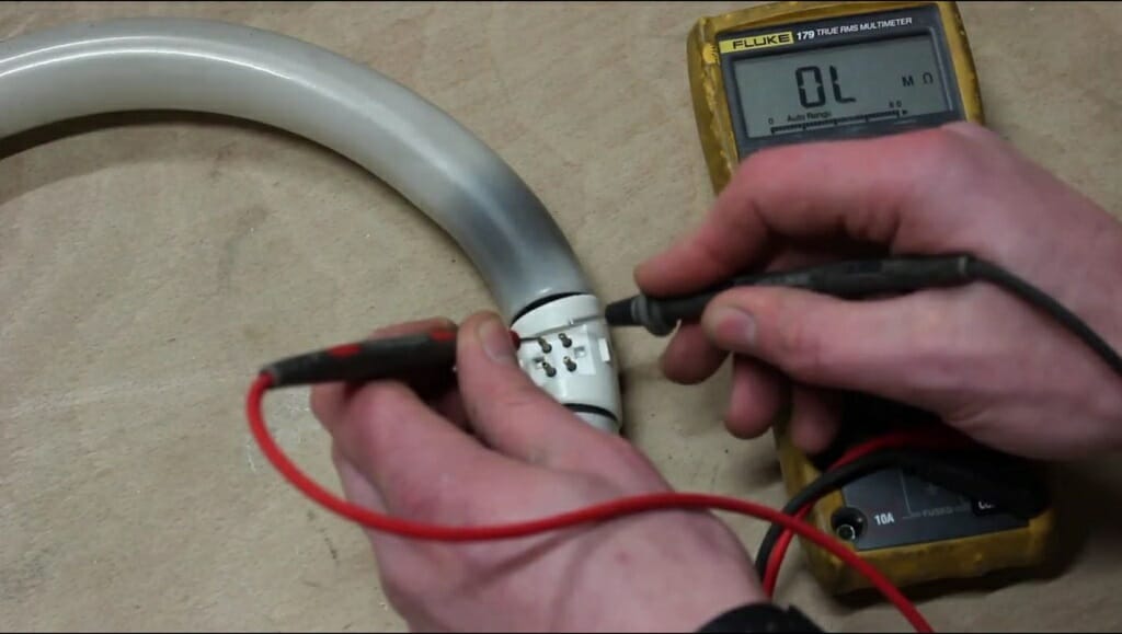 A technician with multimeter testing the florescent bulb