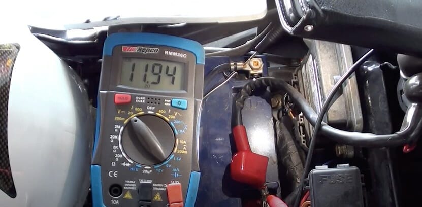testing motorcycle battery with multimeter at 11.94 reading