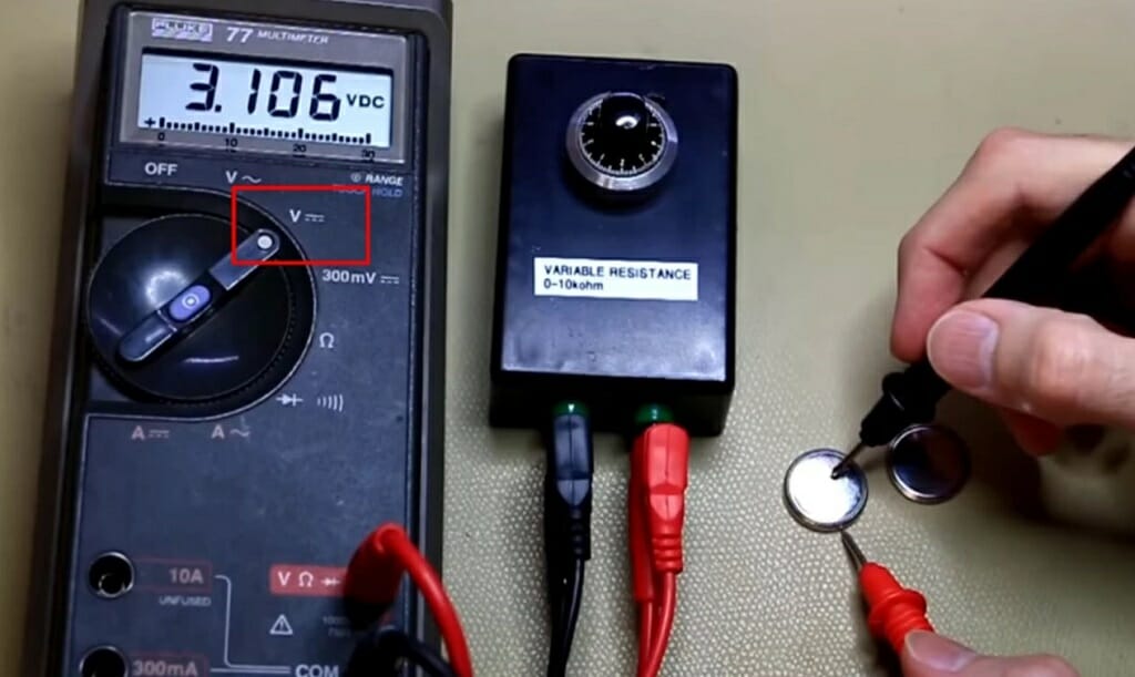 technician testing the watch battery with multimeter at a reading of 3.106 vdc