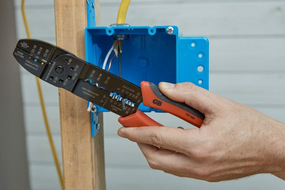 a hand holding a wire stripper with a blue box on the side