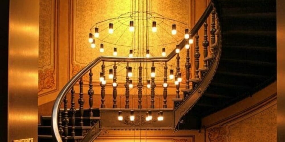 chandelier at a high ceiling just beneath a stair