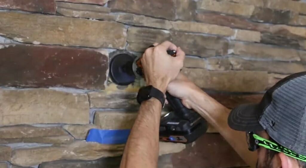man drilling a hole on the brick wall