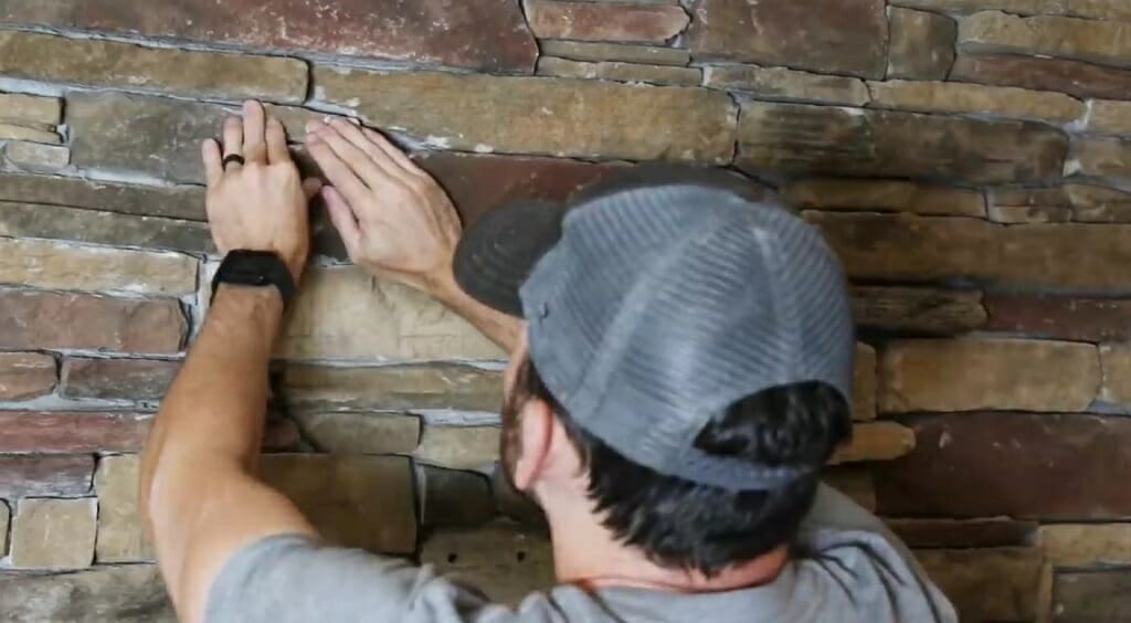 man inspecting and repairing the brick fireplace wall