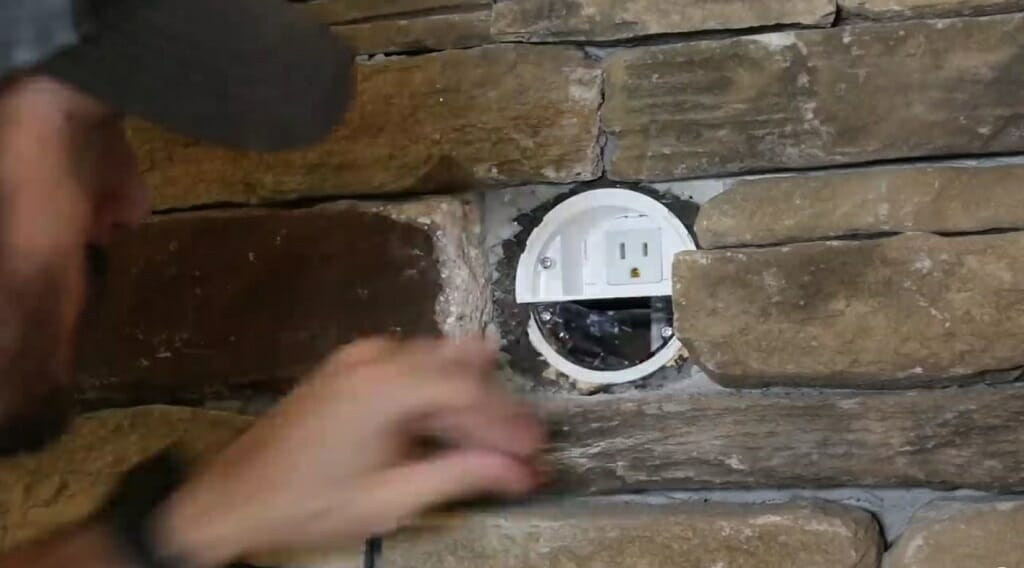man installing female connector to the brick fireplace