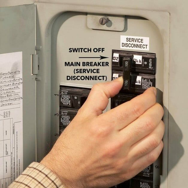 a hand working on a main breaker switch box