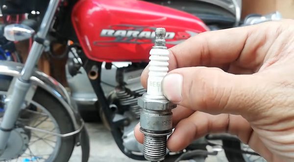 mechanic getting out the spark plug of a Kawasaki motor