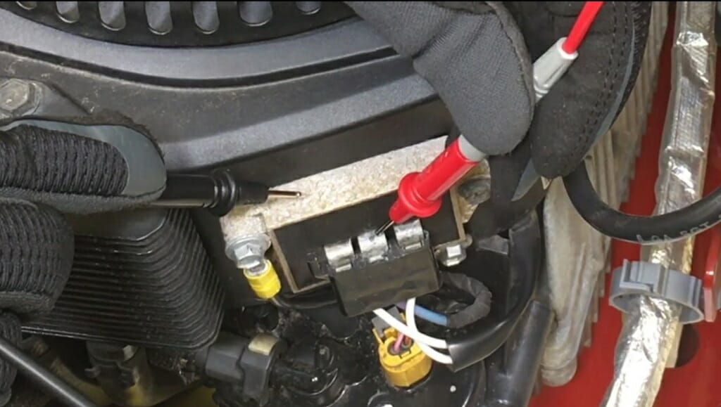 mechanic with black gloves holding red and black multimeter probes