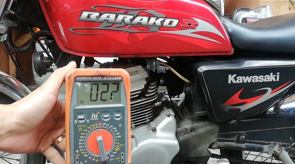 mechanic testing the RPM of a Kawasaki motor with a multimeter at 027v reading