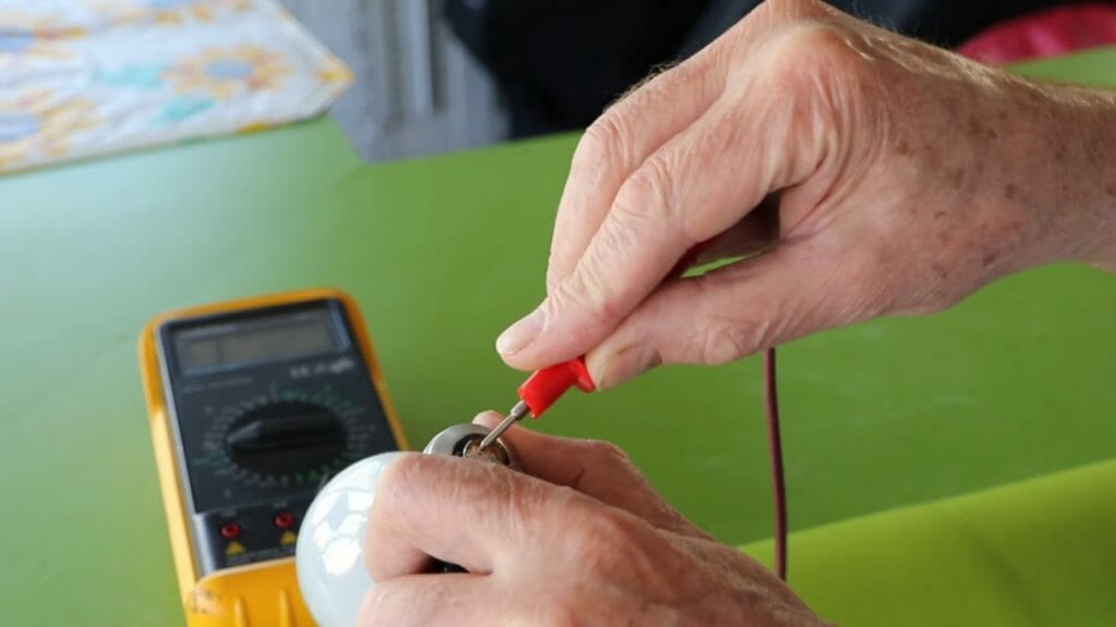 man putting the multimeter's red probe at the halogen bulb for testing