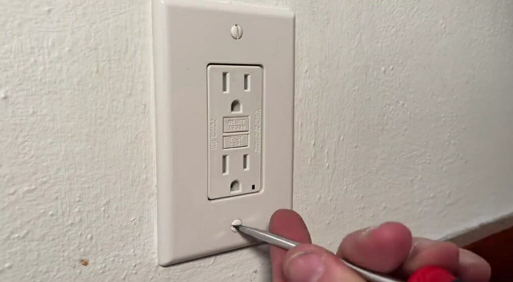 man opening an electrical outlet using screw
