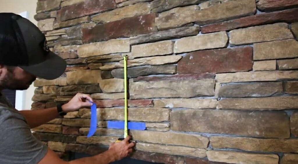 man using tape measure to mark the position of the tv on the fireplace