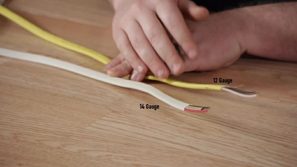 man's hand laying yellow and white gauge wire with 12 and 14 sizes