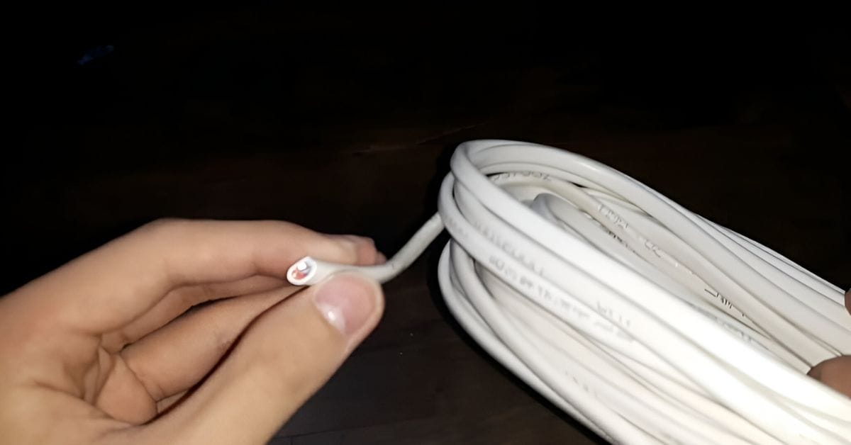 A hand holding a white rolled wire