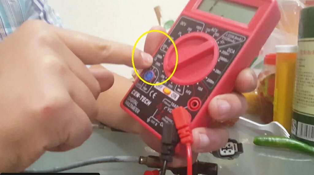 A person setting the multimeter to resistance mode