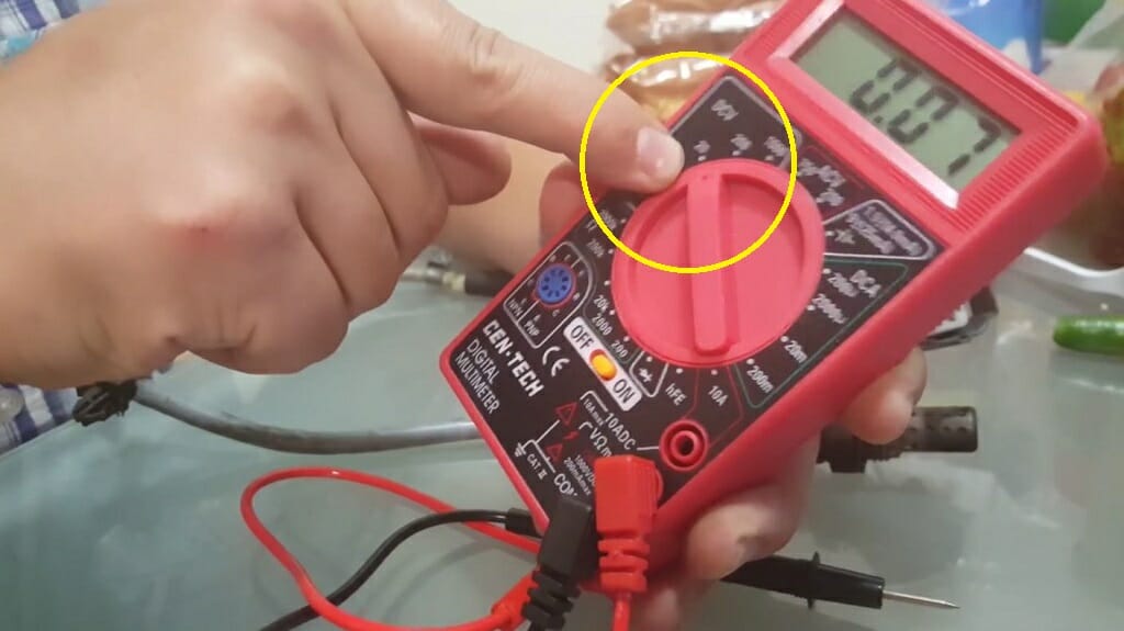 A person setting the multimeter to voltage mode