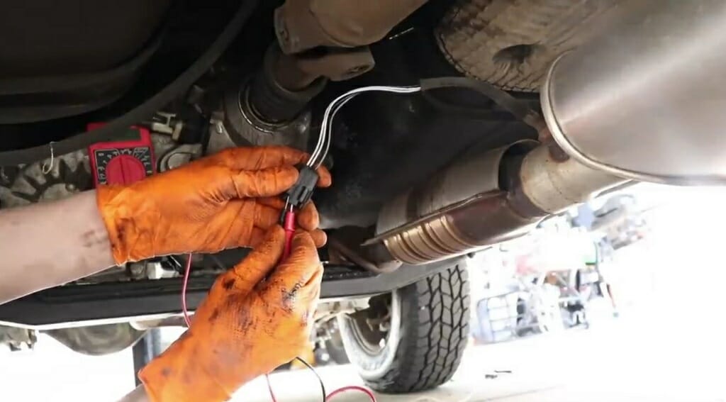 A person wearing an orange gloves testing the signal wires using multimeter