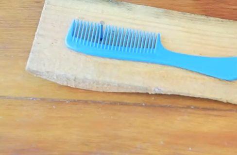 A comb on a nail and piece of wood