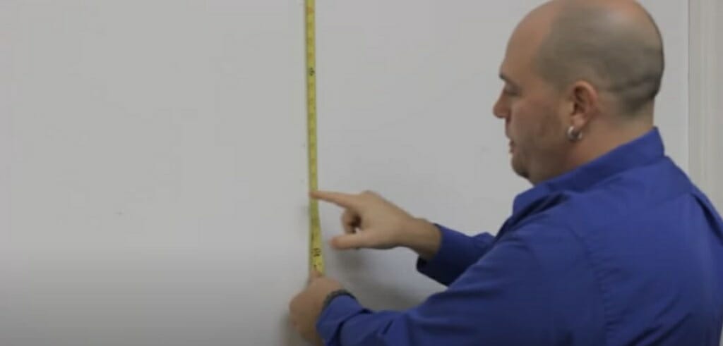 man holding tape measure to find the perfect location for mounting