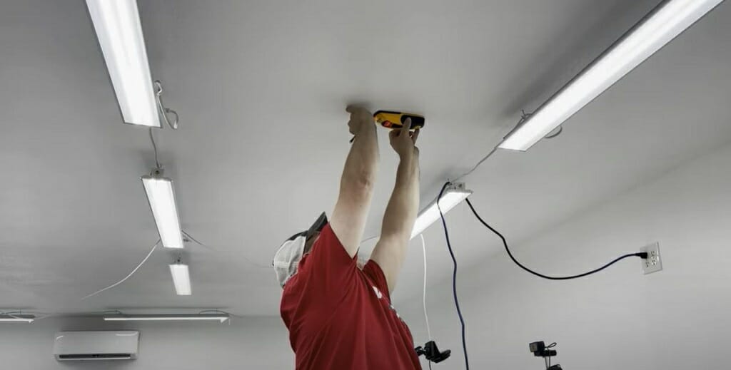 man uses stud finder at the ceiling