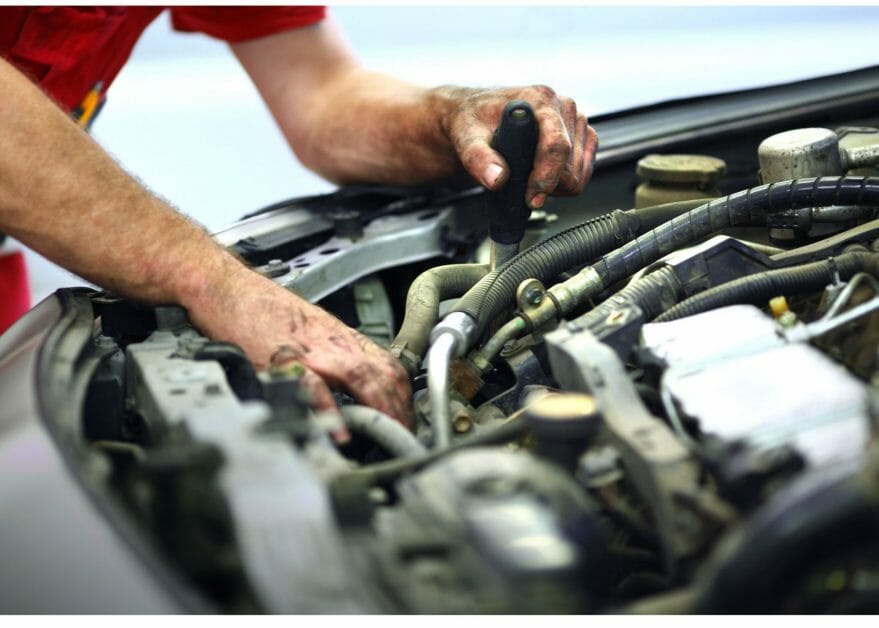 a pair of man's hand repairing car's engine