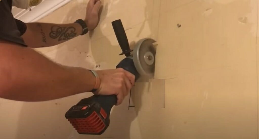 man cutting wall for wire conduit